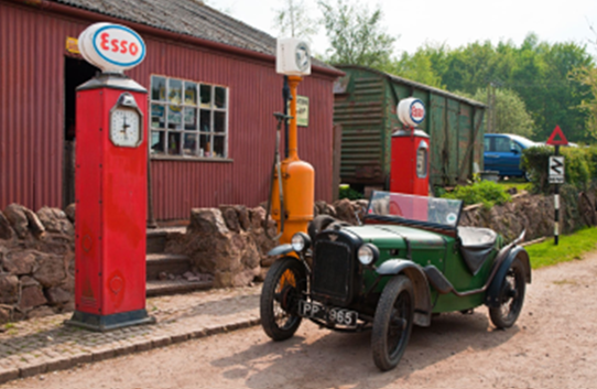 A classic car parked by vintage fuel pumps